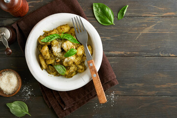 Potato gnocchi. Traditional homemade potato gnocchi with sauce pesto, kitchen table and basil on old dark rustic turquoise kitchen table. Traditional Italian food. Top view.