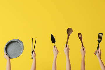 Female hands with baking utensils on yellow background