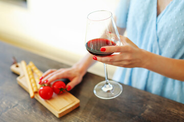Girl holding glass red wine and wooden plate with tomatoes and cheese. Food for wine.