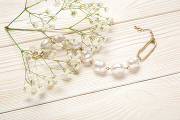 Beautiful pearl bracelet with gypsophila flowers on white wooden background