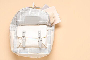 Grey school backpack with different stationery on orange background