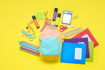 Color school backpack with different stationery on yellow background