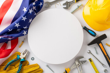 Construction-themed Labor Day tribute: Capture attention with this top-view image, showcasing american flag, work helmet, gloves, and tools on white backdrop. Great for Labor Day campaigns