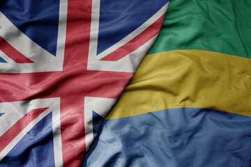 big waving national colorful flag of great britain and national flag of gabon .