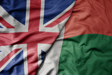 big waving national colorful flag of great britain and national flag of madagascar .