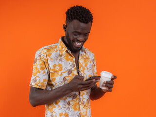 Smiling African American man with cup of coffee and smartphone