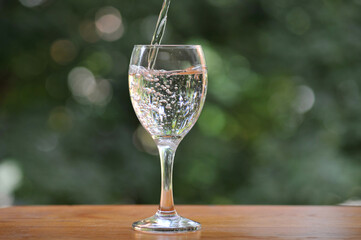 Pouring fresh mineral water from the bottle into a wineglass