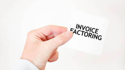 Businessman holding a card with text INVOICE FACTORING business concept