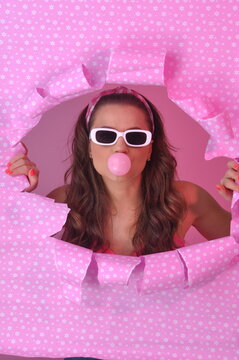 jovem mulher da moda retr&ocirc; fazendo bolha com chiclete em fundo rosa 