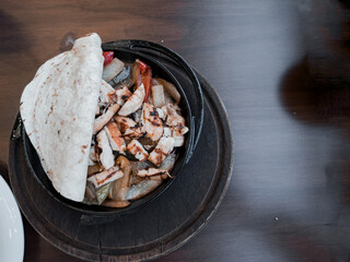 Tray with assorted grilled chicken, vegetables, greens and pita bread over wooden background