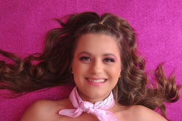bela jovem com maquiagem profissional rosa em fundo rosa com brilho, expressão feliz e sorridente