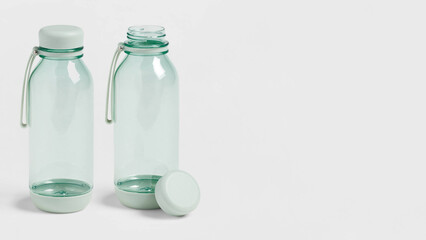 Closeup of two sealed and opened translucent plastic water bottles on copy-space background.