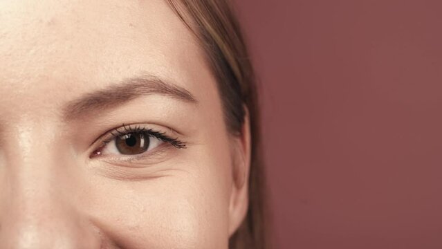 A woman's eye close up. Cropped shot of woman's face in studio on pink background. Good vision and eye care. Contact lenses. Natural female beauty. Cosmetic line for eye contour care.