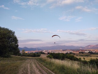 Paraglider flying on the parachute during sunset on the meadow.
