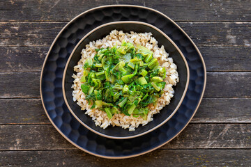 Brown rice topped with stir fry leaves of lettuce and chicory.