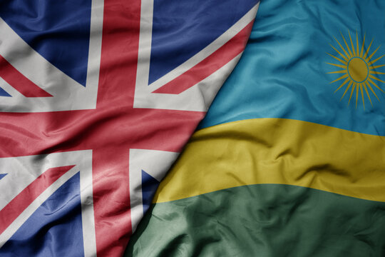 big waving national colorful flag of great britain and national flag of rwanda .