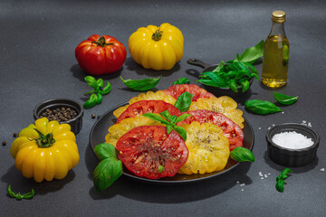 Colorful Heirloom tomato harvest. Ripe ribbed vegetables with fresh basil leaves. Wooden background