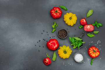 Colorful Heirloom tomato harvest. Ripe ribbed vegetables with fresh basil leaves. Wooden background