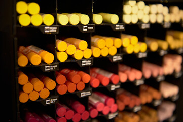 Colorful pencils in warm colors spectrum for drawing pastels, displayed for sale on shelf in the school stationery store