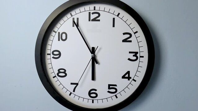Closeup of White Clock Face on white wall clock, arrows show 6:00 or 00:00