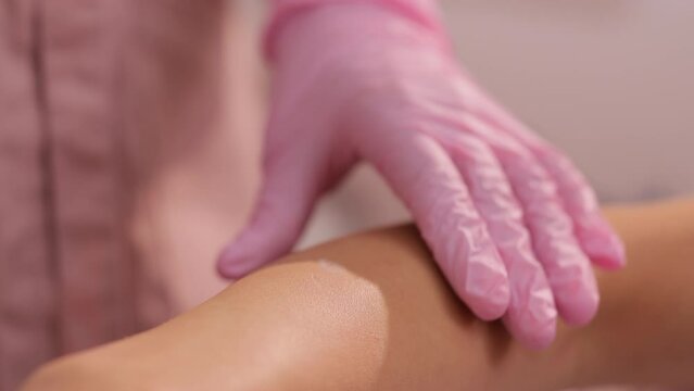 Laser hair removal specialist draws on moles on the woman's hand with a protective pencil. Women's hands in gloves mark the area for epilation and protection of moles with a pencil
