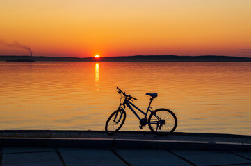 Fototapeta premium Landscape with a bicycle on the shore of the lake at sunset