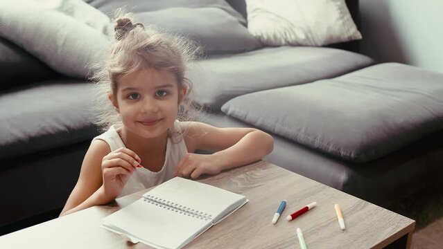 An adorable 5-year-old girl at home, engrossed in her colouring activity using vibrant markers. Captured in a cozy setting, she brings her imagination to life on a coffee table.