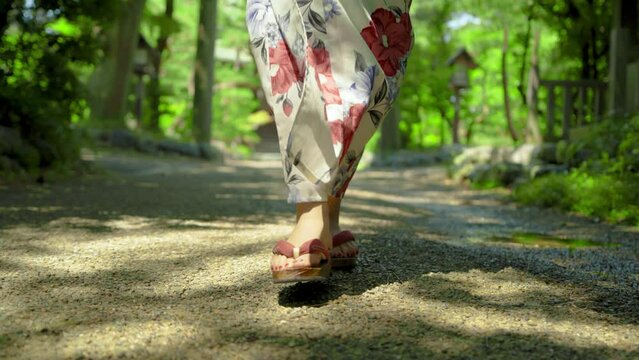 神社の参道を歩く浴衣姿の日本人女性の足元