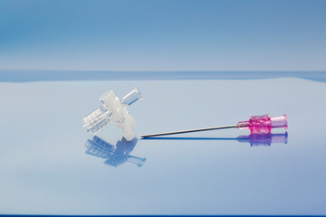 Medical devices used during diagnosis and drainage of liquid and gas accumulation in the pleural cavity. Three-way stopcock and percutaneous entry needle on light blue background