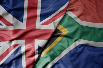 big waving national colorful flag of great britain and national flag of south africa .