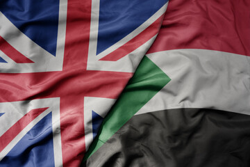 big waving national colorful flag of great britain and national flag of sudan .