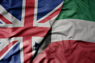 big waving national colorful flag of great britain and national flag of kuwait .
