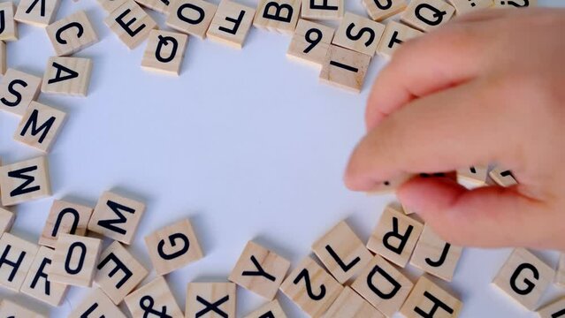 female hand close-up holds wooden alphabet blocks, makes up words iq from wooden letters on white background, intelligence quotient, intellectual achievements, idea, human brain development concept - Powered by Adobe