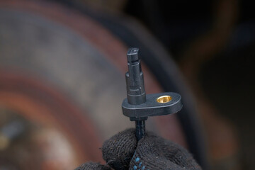 Worker hold in hand new ABS sensor, replace damaged electrical sensor. Technician hand holding...