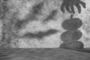 Scary silhouettes on a concrete gray wall from bats, a stack of pumpkins, a zombie hand. Abstract...