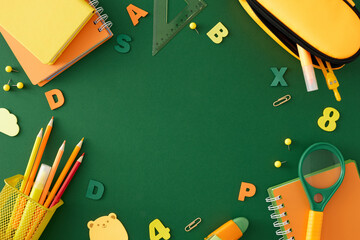 Highlighting the core of education. Top view arrangement of stationery for the school, yellow, orange, green letters and numbers on green background with blank space for promo or text