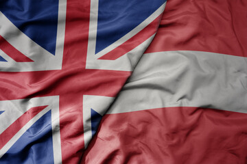 big waving national colorful flag of great britain and national flag of austria .