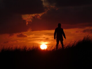Silhouette eines Jungen auf der D&uuml;ne beim Sonnenuntergang