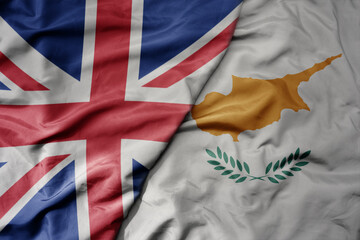 big waving national colorful flag of great britain and national flag of cyprus .