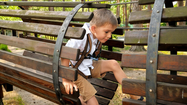 Little boy crawling through wooden pipe or tunnel on playground at park. Active childhood, healthy lifestyle, kids playing outdoors, children in nature - Powered by Adobe