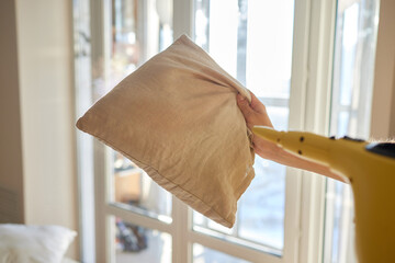 Woman steaming pillow at home, closeup view.