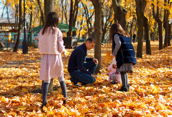 portrait of a family with children in an autumn city park, happy people walking together, playing with yellow leaves, beautiful nature, bright sunny day