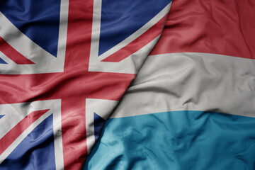 big waving national colorful flag of great britain and national flag of luxembourg .