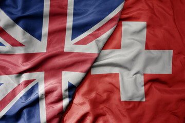 big waving national colorful flag of great britain and national flag of switzerland .