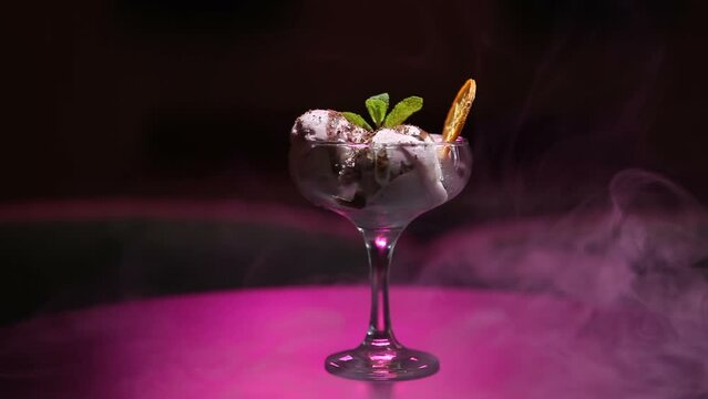 Cold sweet dessert ice cream, rotates on a dark background, hookah smoke in the background. The video was filmed in a bar.