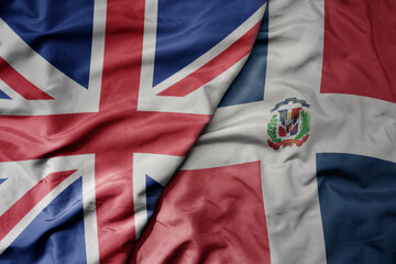 big waving national colorful flag of great britain and national flag of dominican republic .