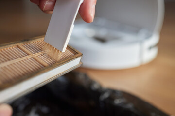 Cleaning the filter of the vacuum robot cleaner from dirt, close-up.