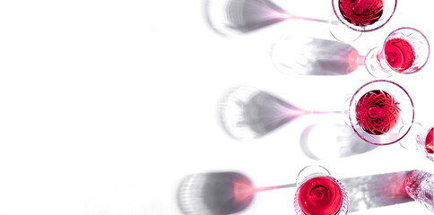 Glasses with pink red wine and sparkling shadows on white background. Shadows from glasses of wine...
