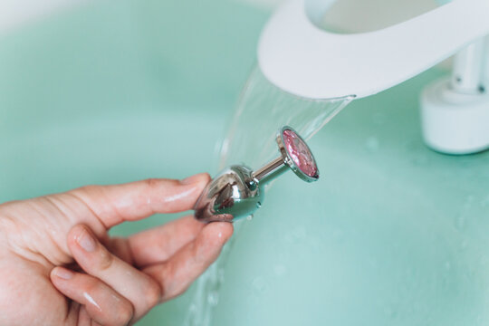 Hands washing metal anal plug, caring for sex toys