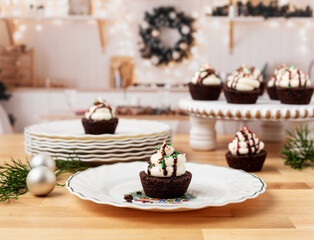 Chocolate Brownie Cupcakes with Buttercream Frosting and Red , Green, and Gold Christmas Sprinkles on Christmas Plates on Butcher Block Countertop in Kitchen Decorated for Christmas